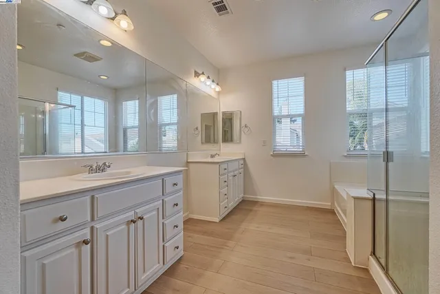 a bathroom with a double vanity sink and mirror with shower