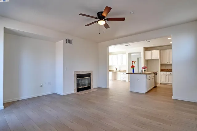 a view of empty room with wooden floor and a ceiling fan
