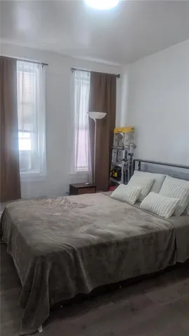 a bedroom with a bed wooden floor and window