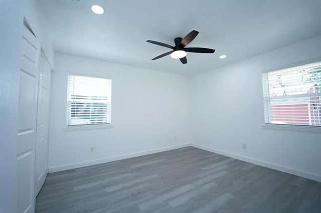 a view of an empty room with a window and wooden floor