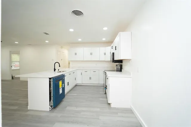 a kitchen with white cabinets and sink
