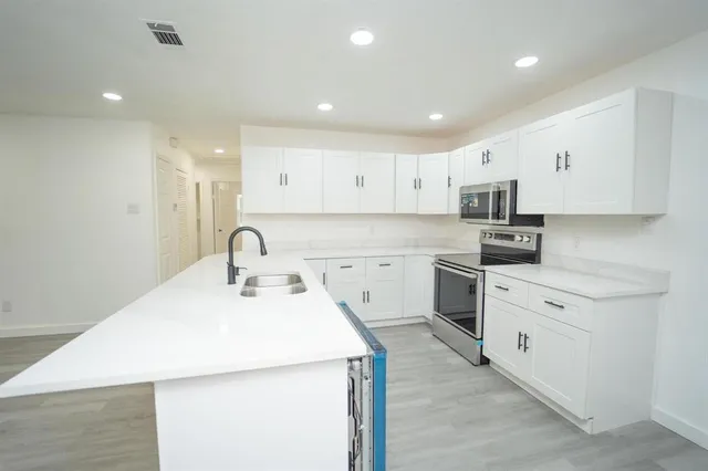 a kitchen with a sink a stove and white cabinets