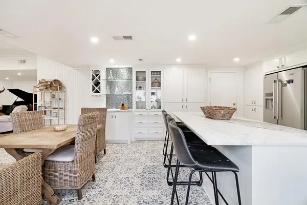 a kitchen with stainless steel appliances kitchen island granite countertop a table chairs and a refrigerator