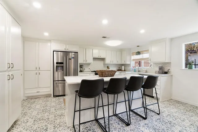 a kitchen with a dining table chairs and refrigerator