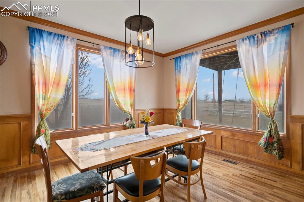 20880 Scott Road Calhan, CO 80808 - Photo 14 of 39 a dining room with wooden floor a chandelier a glass table and chairs