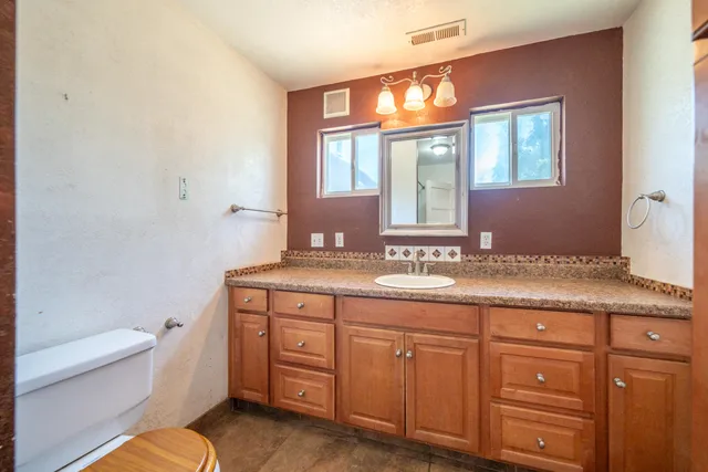 a bathroom with a granite countertop toilet sink and mirror