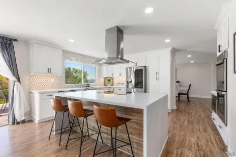 a large kitchen with stainless steel appliances granite countertop a table chairs sink and cabinets