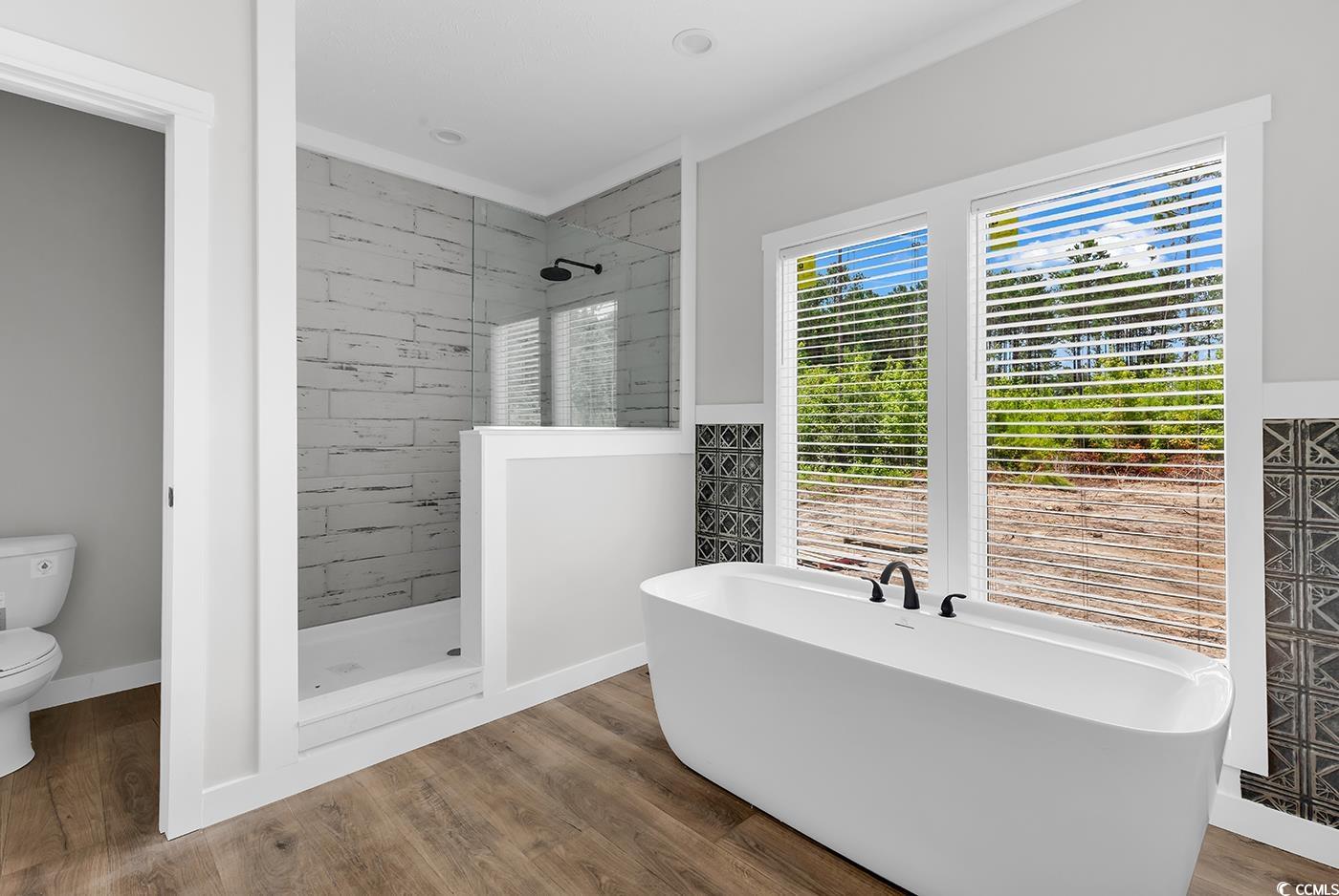 754 Kent Road Andrews, SC 29510 - Photo 29 of 31 Full bathroom with a freestanding tub, vanity, a shower stall, light wood-type flooring, and wainscoting