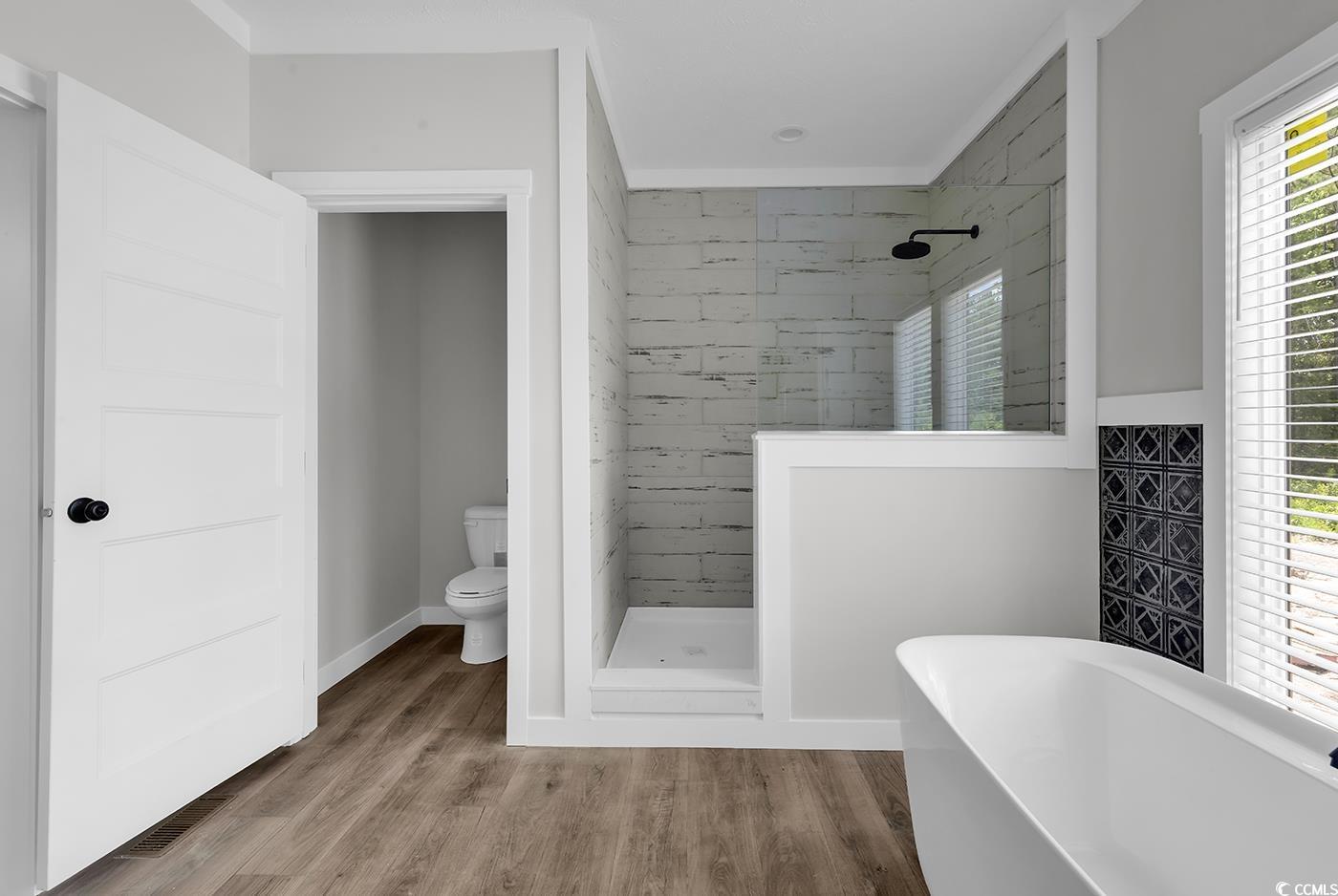 754 Kent Road Andrews, SC 29510 - Photo 30 of 31 Full bathroom featuring double vanity, a soaking tub, light wood-style floors, wood walls, and a wainscoted wall