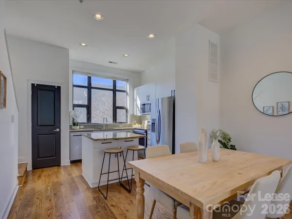 a kitchen with stainless steel appliances a dining table chairs refrigerator and sink