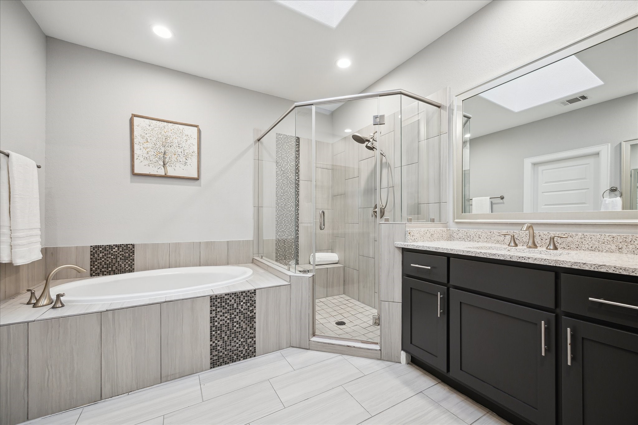 2430 Sheridan Street Houston, TX 77030 - Photo 16 of 28 Indulge in a spa-like escape with a luxurious soaking tub and a separate walk-in shower featuring a seamless glass door. This elegant primary bathroom combines modern sophistication with comfort, creating a serene retreat within the home.