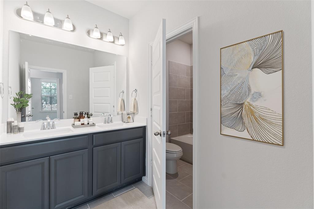 715 Soprano Drive Forney, TX 75126 - Photo 13 of 16 a bathroom with a double vanity sink a toilet and a mirror