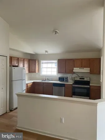 a kitchen with stainless steel appliances granite countertop a refrigerator a sink a stove a microwave a counter space and cabinets