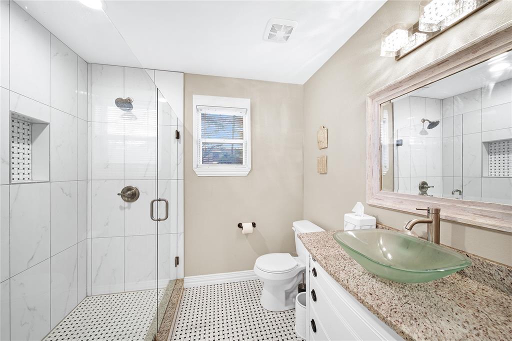 828 Elsbeth Street Dallas, TX 75208 - Photo 29 of 35 a bathroom with a granite countertop sink a toilet a mirror and shower