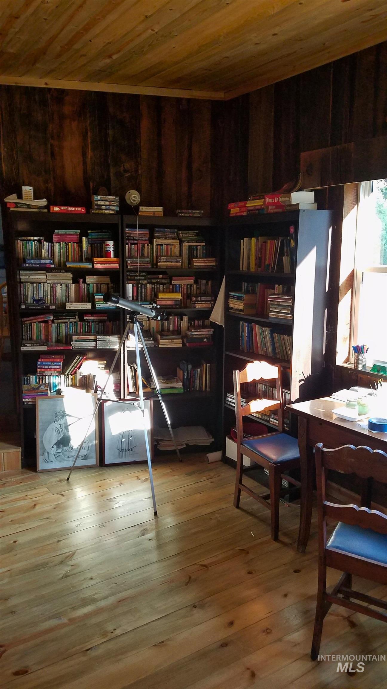 27 Grizzly Lane Challis, ID 83226 - Photo 13 of 47 Living area featuring wood ceiling, light wood finished floors, wood walls, and wall of books