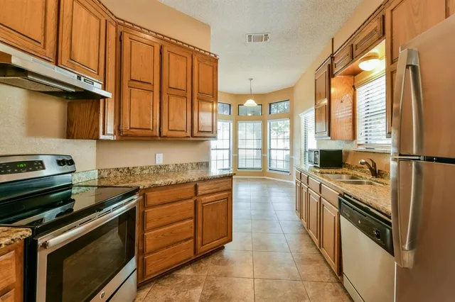 a kitchen with stainless steel appliances granite countertop a stove a sink and a refrigerator