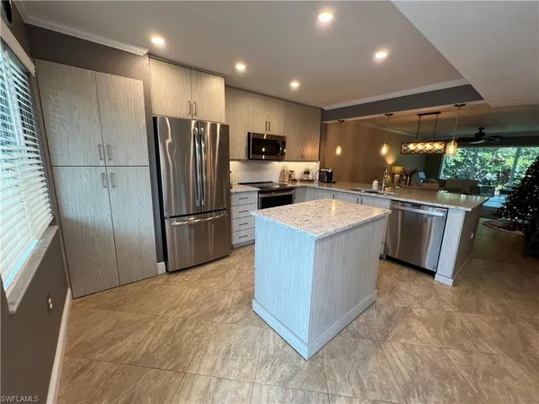 a kitchen with stainless steel appliances granite countertop a refrigerator a sink a stove a microwave and island