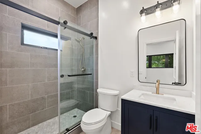 a bathroom with a toilet a sink a mirror and shower