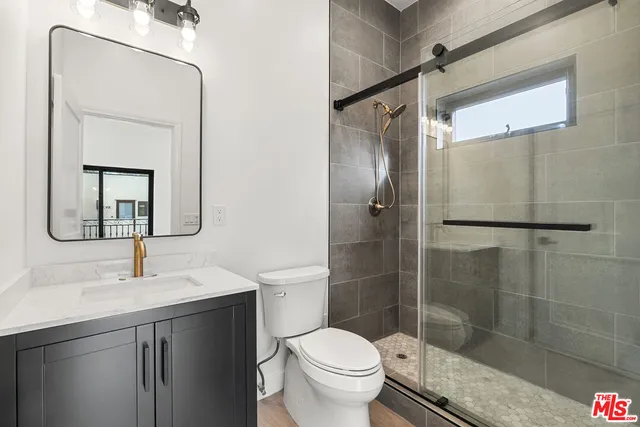 a bathroom with a shower sink vanity mirror and toilet
