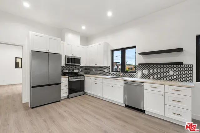 a kitchen with granite countertop white cabinets and stainless steel appliances