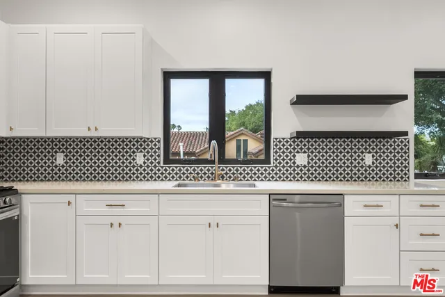 a kitchen with white cabinets and window