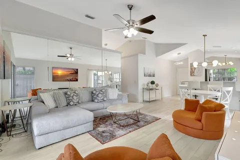 a living room with furniture kitchen view and a chandelier