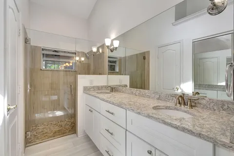 a bathroom with a granite countertop sink a mirror and shower