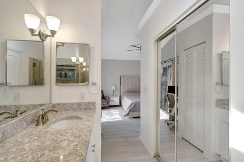a bathroom with a granite countertop sink mirror and cabinets