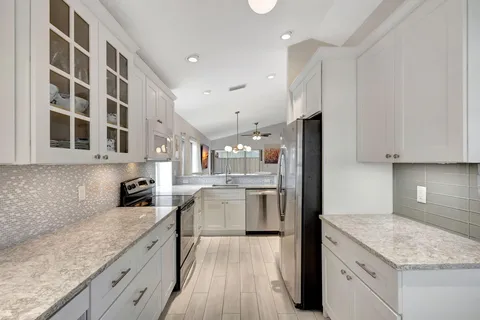 a kitchen with a sink dishwasher a refrigerator and white cabinets with wooden floor