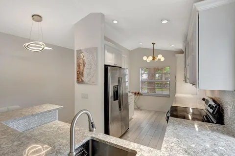 a kitchen with stainless steel appliances granite countertop a refrigerator a sink a stove and a wooden floors