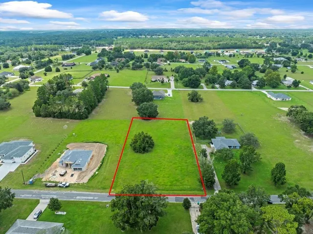 an aerial view of a residential houses with outdoor space and a lake view in back