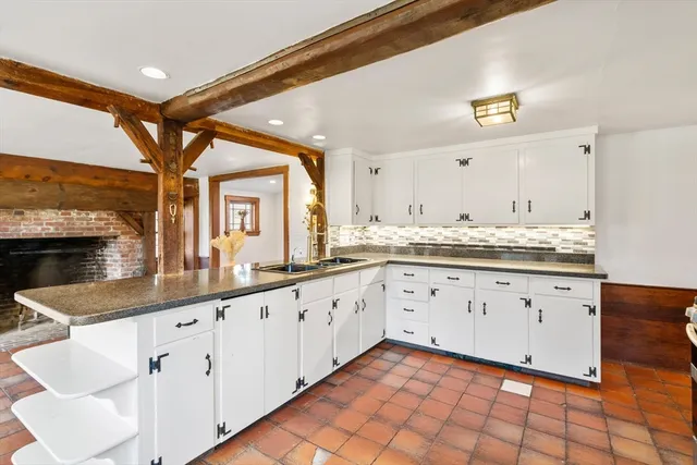 a large white kitchen with granite countertop a sink and white cabinets