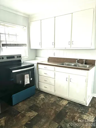 a kitchen with granite countertop a sink a stove and cabinets