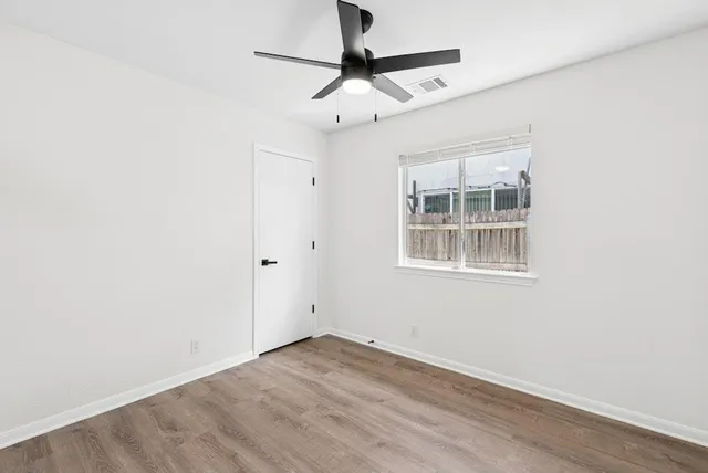 a view of empty room with wooden floor and ceiling fan