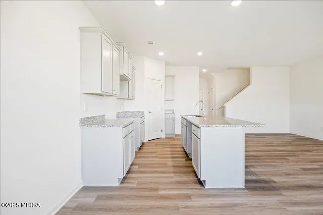 a kitchen with kitchen island sink and white cabinets