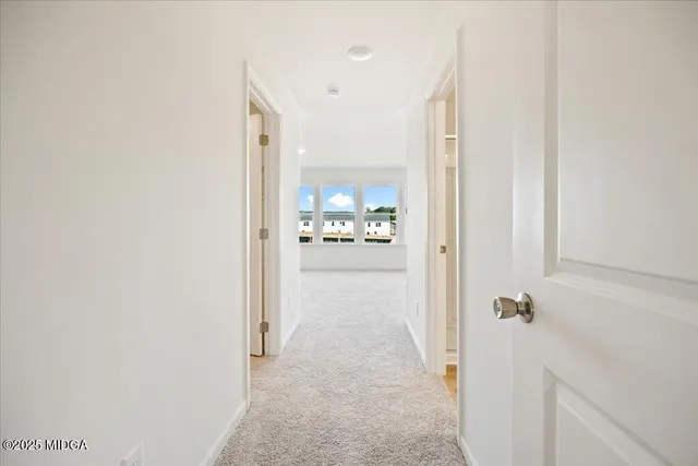 a view of a hallway with wooden floor and a bathroom