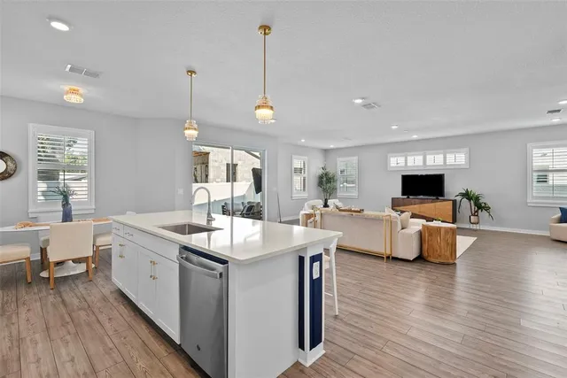 a large white kitchen with a large island oven a sink dishwasher a dining table and chairs with wooden floor