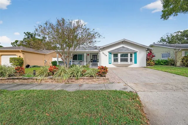 a front view of a house with a yard and potted plants