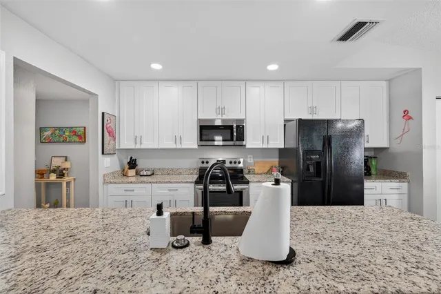 a kitchen with stainless steel appliances granite countertop a stove a refrigerator a kitchen island and chairs in it