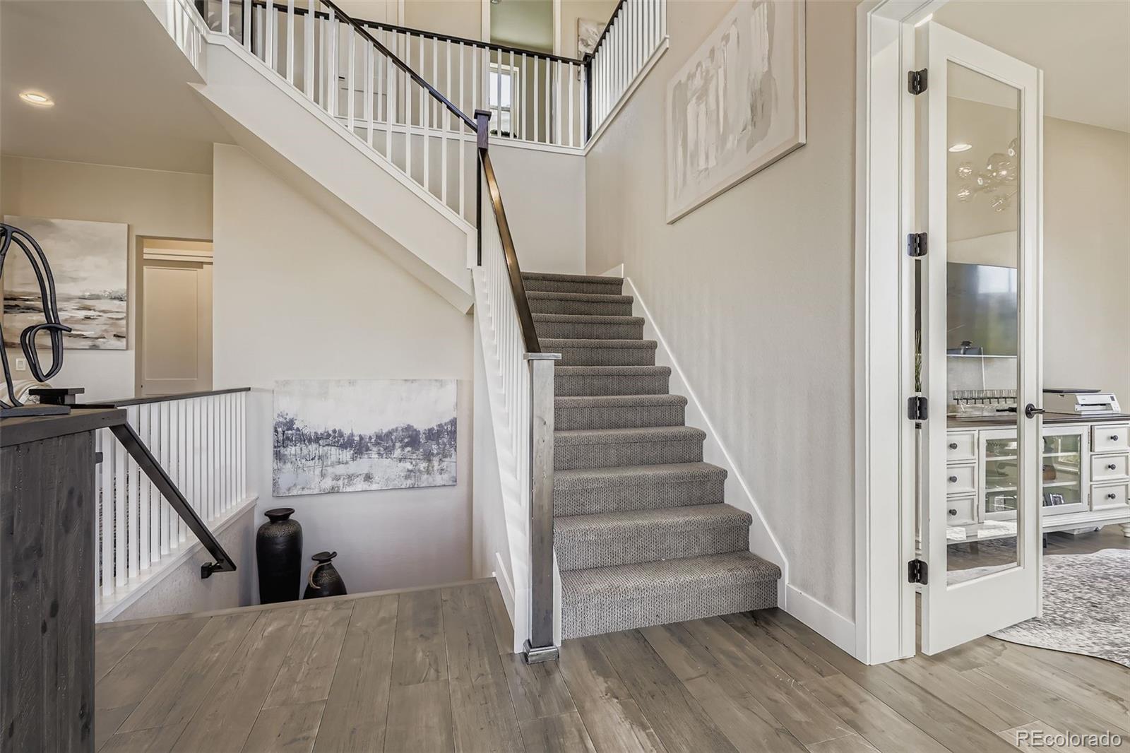 10414 Maplebrook Way Highlands Ranch, CO 80126 - Photo 15 of 45 a view of staircase with lots of frames on wall and wooden floor