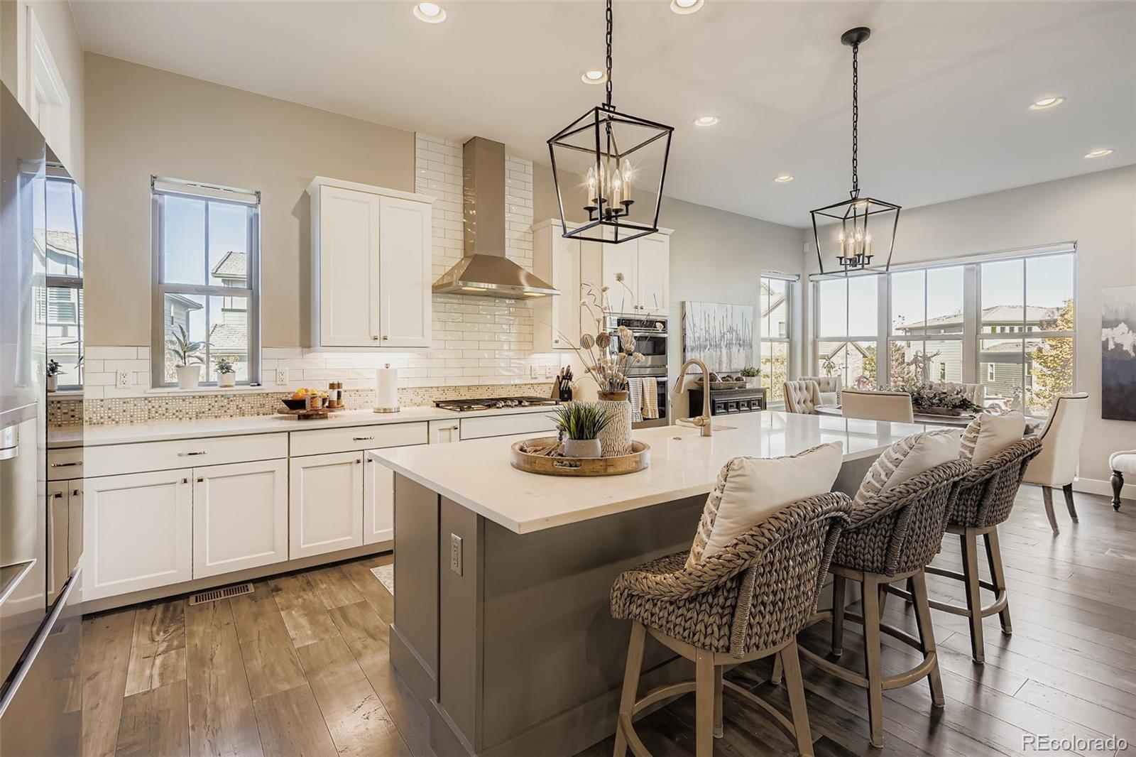 10414 Maplebrook Way Highlands Ranch, CO 80126 - Photo 4 of 45 a kitchen with stainless steel appliances kitchen island granite countertop a sink a stove a dining table and chairs