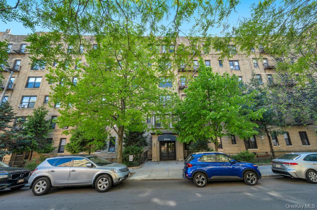 83-64 Talbot Street, Unit 3A Queens, NY 11415 - Photo 1 of 15 Multi-story brick facade building featuring numerous windows, prominent fire escapes, and a ground-level recessed entryway with dark double doors