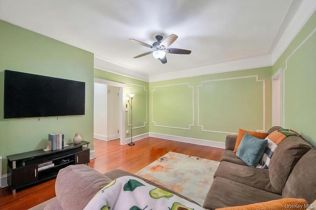 83-64 Talbot Street, Unit 3A Queens, NY 11415 - Photo 3 of 15 Living area featuring wood-finish flooring, decorative wall molding, a ceiling fan with integrated lighting, and a wide doorway