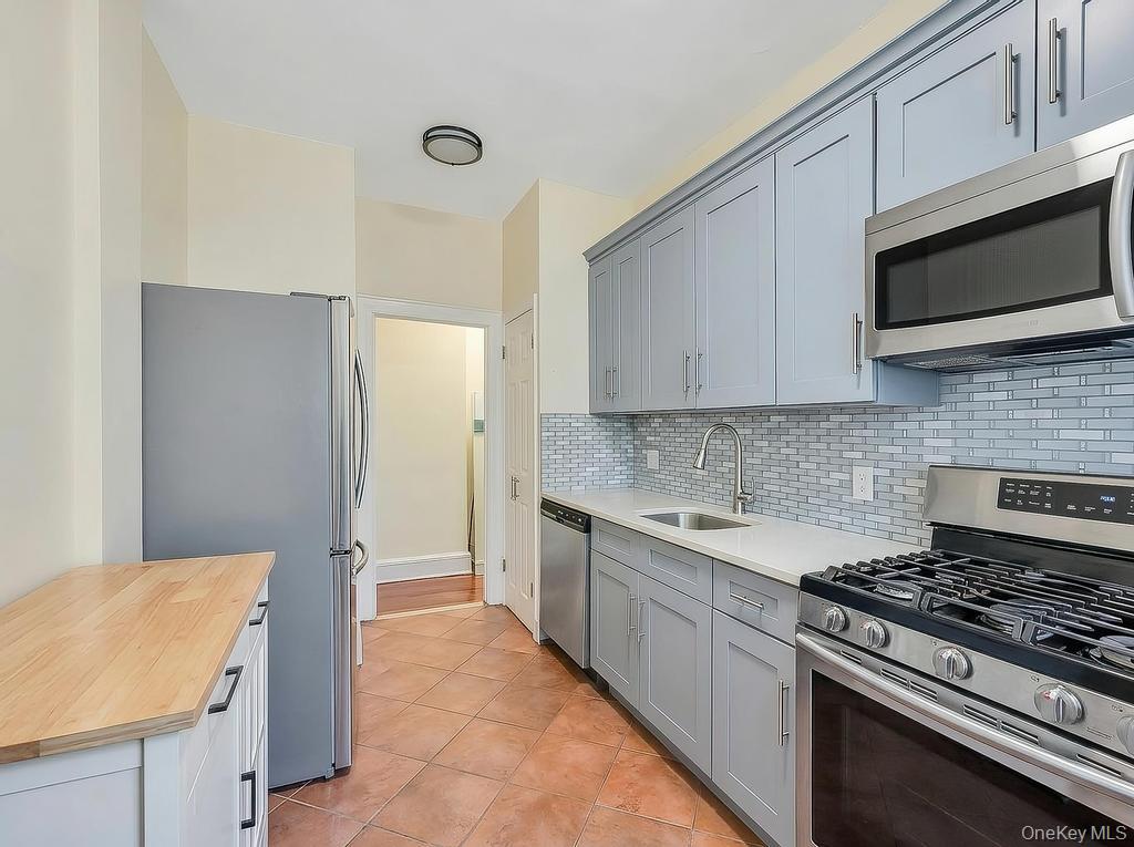 83-64 Talbot Street, Unit 3A Queens, NY 11415 - Photo 5 of 15 Updated kitchen with stainless steel appliances, light gray cabinetry, white countertops, and a white subway tile backsplash