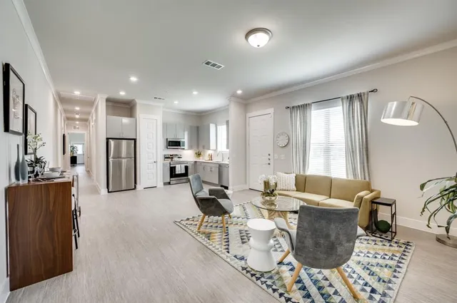 a living room with furniture kitchen view and a large window