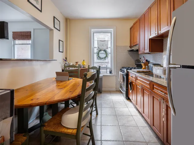 a kitchen with stainless steel appliances kitchen island a table chairs in it and wooden floors
