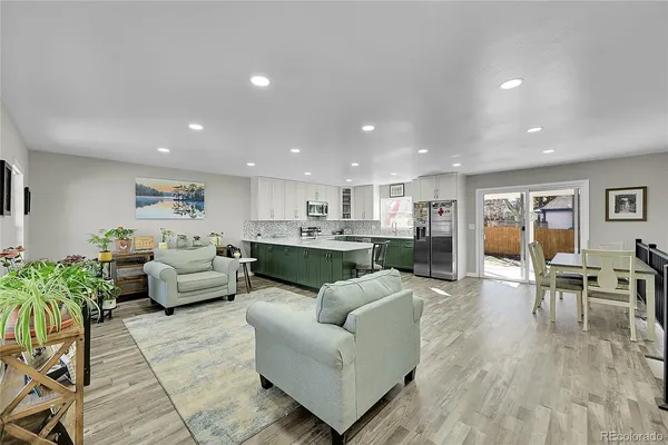 a living room with furniture kitchen view and a wooden floor