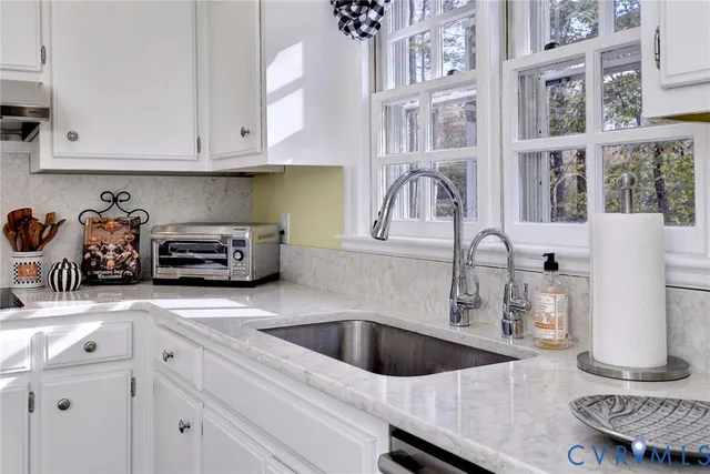 a kitchen with stainless steel appliances granite countertop a sink and a white cabinets