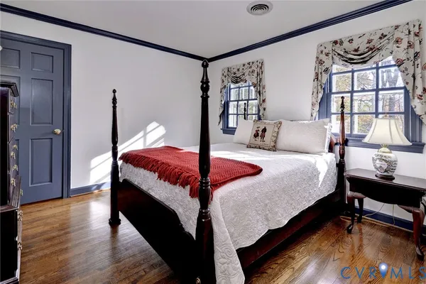 a bedroom with a bed lamp and a large window with wooden floor