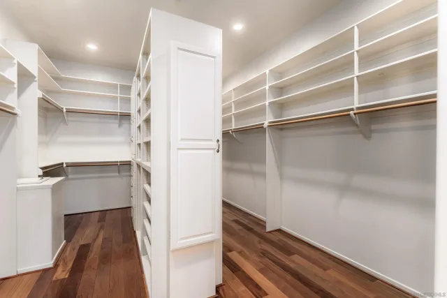 an empty room with wooden floor and a ceiling fan
